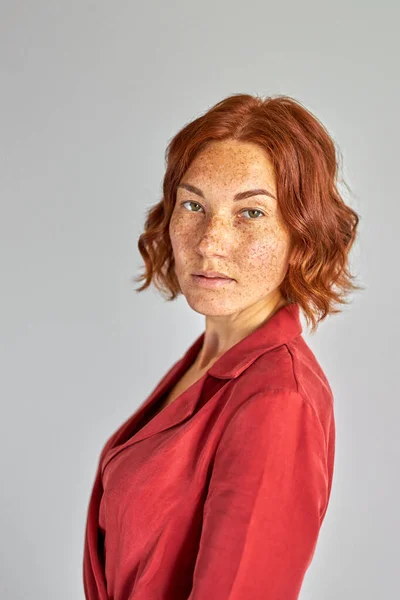 Schöne rothaarige Frau mit Sommersprossen schaut in die Kamera — Stockfoto