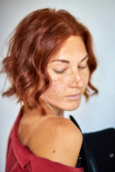 Retrato de adorável ruiva senhora olhando para baixo e segurando chapéu preto nas mãos — Fotografia de Stock