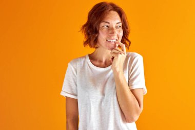 Gündelik giysiler içindeki mutlu kızıl kadın derin düşüncelere dalmış, hayal kuruyor.