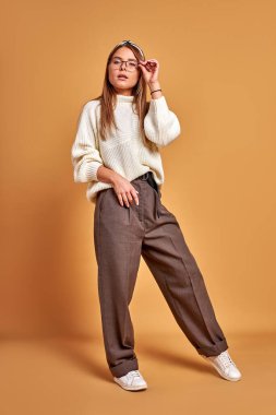 Gözlüklü kadın kameraya özgüvenle bakıyor.