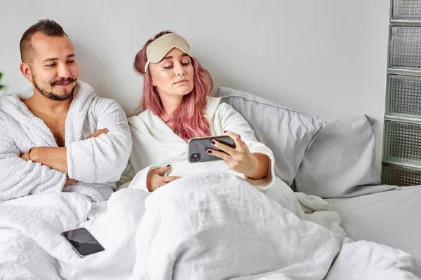 멋진 여인이 남편과 함께 침대에 누워 사진을 찍는다 — 스톡 사진