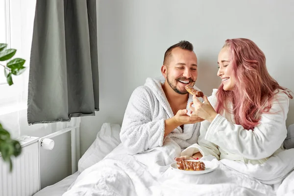 Couple joyeux manger éclairs le matin — Photo