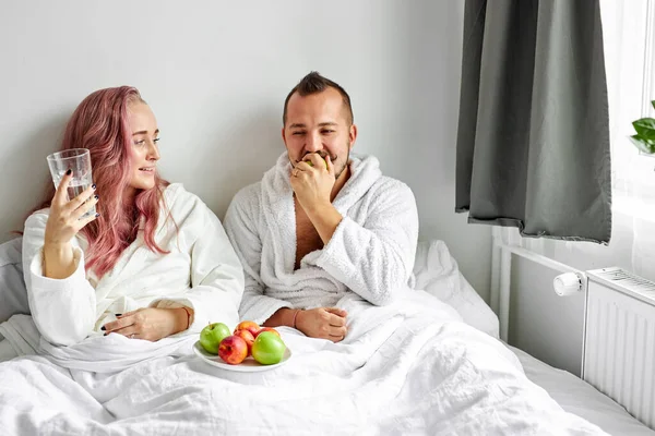 Adorable woman and man enjoy having meal on bed in the morning — Stock Photo, Image