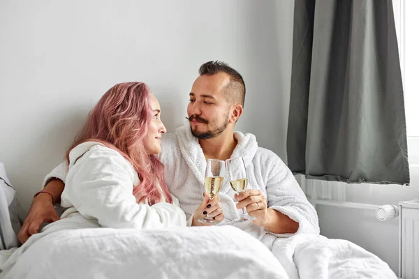 Linda mulher e homem em vestes brancas deitado na cama e desfrutando de tempo juntos — Fotografia de Stock