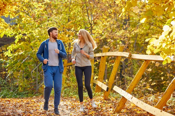 一对运动型的夫妇在秋天的森林里赛跑 — 图库照片