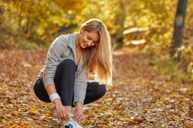 Atletik genç kadın dışarı çıkmadan önce spor ayakkabılarının bağcıklarını bağla.