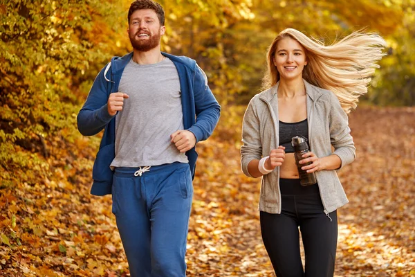 sportive athletic couple run together in the autumn forest