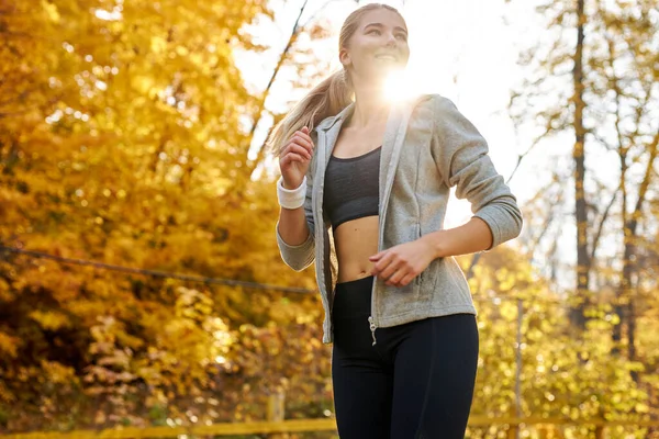 Uitzicht van onderaf op fitte vrouw rennend in het bos — Stockfoto