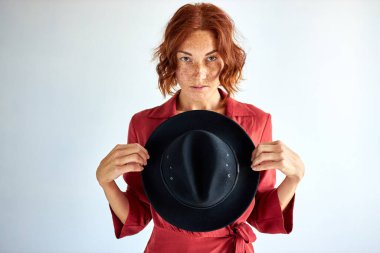 Elinde siyah şapkası olan kendine güvenen bir kadın stüdyoda izole edilmiş.