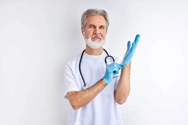 Hombre de edad avanzada está usando guantes y mirando a la cámara, la atención médica y el concepto de preparación — Foto de Stock