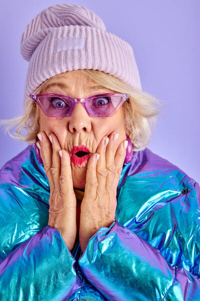 пожилая очаровательная женщина, держась за руки возле щек с широко открытыми глазами и ртом