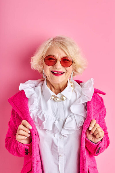 happy optimistic aged lady in blouse and coat smiles