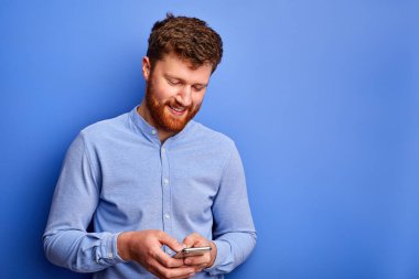 Gülümseyen sakallı adam akıllı telefondan biriyle konuşuyor.