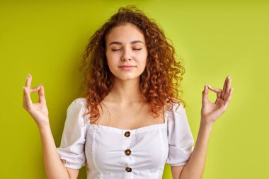 Kıvırcık kadın namaste 'de ya da duada el ele tutuşuyor, meditasyon yapıyor.