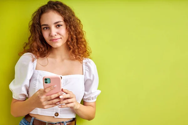 Lindo rizado adolescente chica disfrutar de chatear con alguien utilizando el teléfono móvil — Foto de Stock