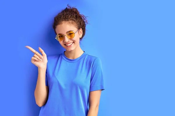 Positiv lächelndes Teenie-Mädchen, das mit dem Finger auf die Seite zeigt, Zeigefinger — Stockfoto