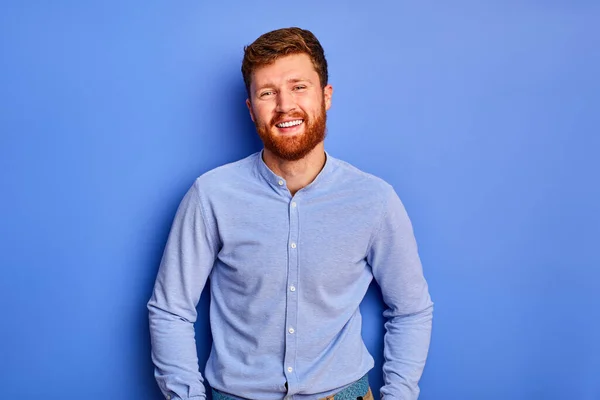 Optimista caucásico chico en azul elegante camisa sonrisas a cámara aislada —  Fotos de Stock