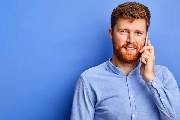 Knappe blanke man heeft een leuk gesprek met iemand aan de telefoon — Stockfoto