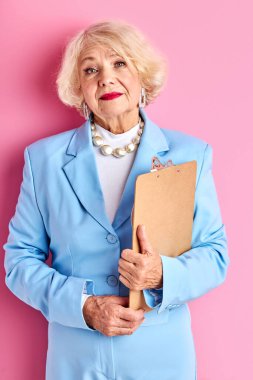 Tabletli yaşlı bayan öğretmen pembe arka planda izole edildi