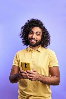 pozitif kıvırcık erkek mor arkaplanda izole akıllı telefon kullanır