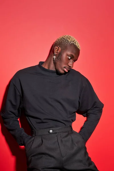 Unusual portrait of young afro american male model in studio with red background — Stock Photo, Image