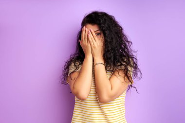 Korkmuş kıvırcık saçlı kadın yüzünü kapatıyor.