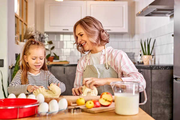 Caucasiano criança filha ajudando a mãe amassar preparando massa na cozinha moderna — Fotografia de Stock