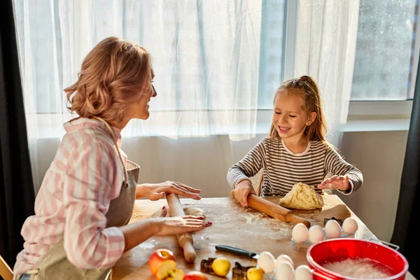 Młoda mama uczyć mała córka zrobić ciasto pracy używać wałek pin w kuchni — Zdjęcie stockowe