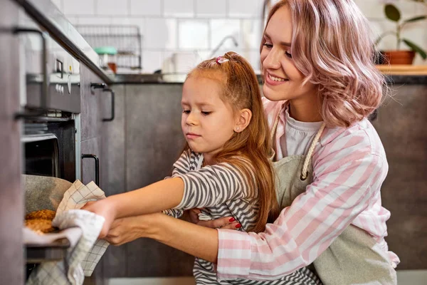 Feliz joven madre y lindo niño hija hornear galletas en la cocina — Foto de Stock