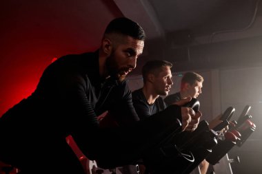 spor salonunda bisiklete binen aktif erkekler