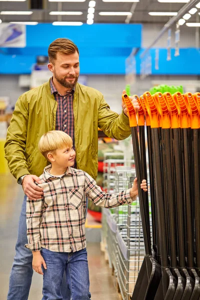 child boy and father choosing shovel for the garden