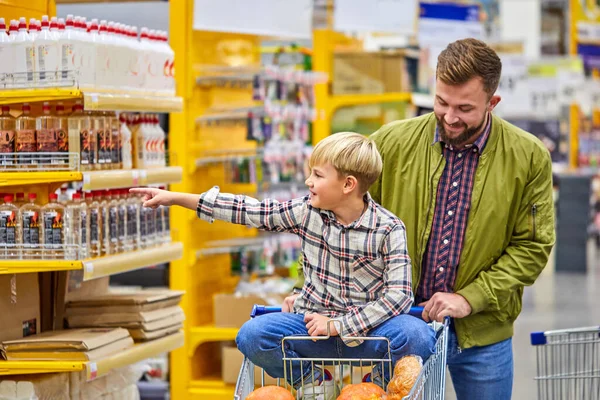 Positieve kind jongen geniet van winkeltijd met vader in supermarkt — Stockfoto