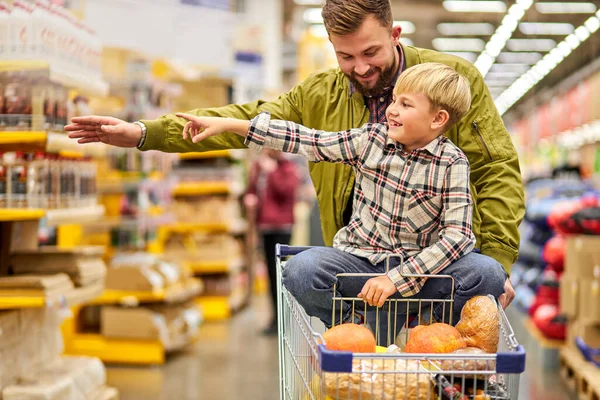 Jongen wijzen vinger naar de zijkant in de winkel tijdens het winkelen met vader — Stockfoto