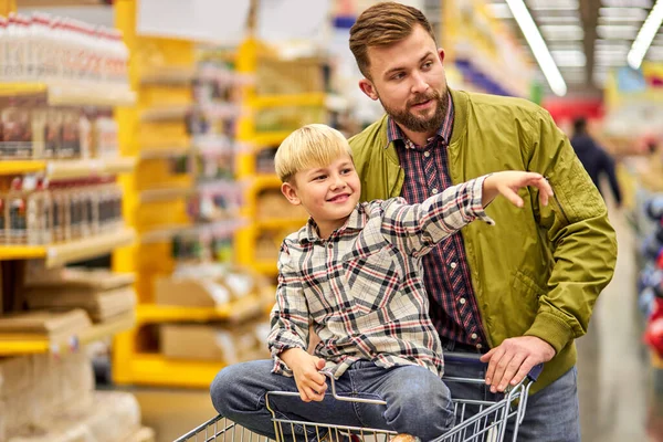 Menino positivo gosta de fazer compras com o pai no supermercado — Fotografia de Stock