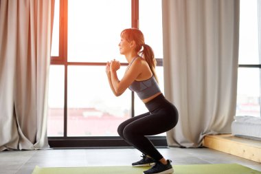 Asyalı formda bir kadının evde çömelmesi üzerine yan görüş