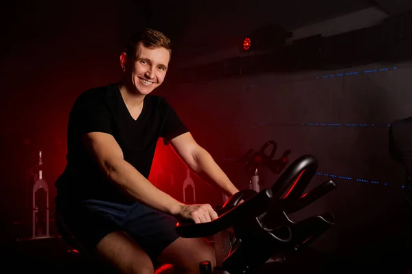 Πορτρέτο του χαρούμενου αθλητή σε σταθερό maching ποδήλατο στο γυμναστήριο — Φωτογραφία Αρχείου