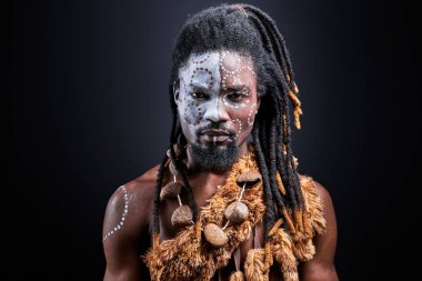 Renkli makyajlı, esrarengiz Afrikalı gömleksiz adam tecrit edilmiş.