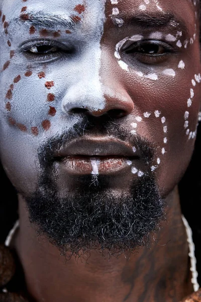serious african male with ethnic paintings on face look at camera