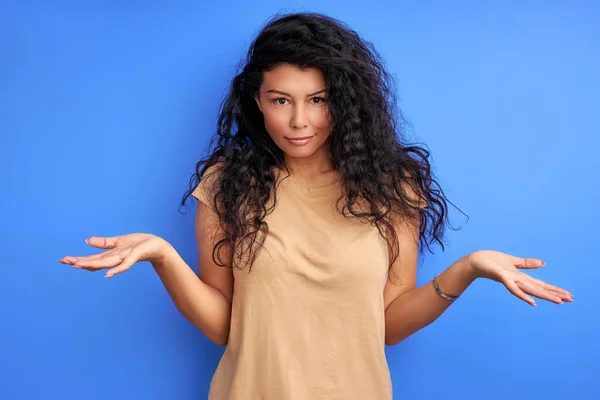 Mladá dospělá žena s kudrnaté černé vlasy pokrčení rameny nedorozumění — Stock fotografie