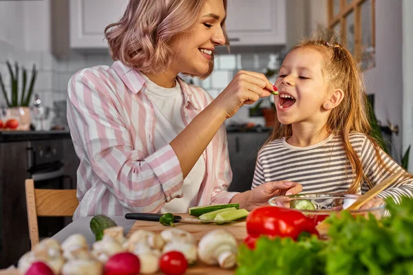 Niedliche Mutter und Kind Mädchen Verkostung frischer Früchte während der Zubereitung von Salat zum Abendessen — Stockfoto