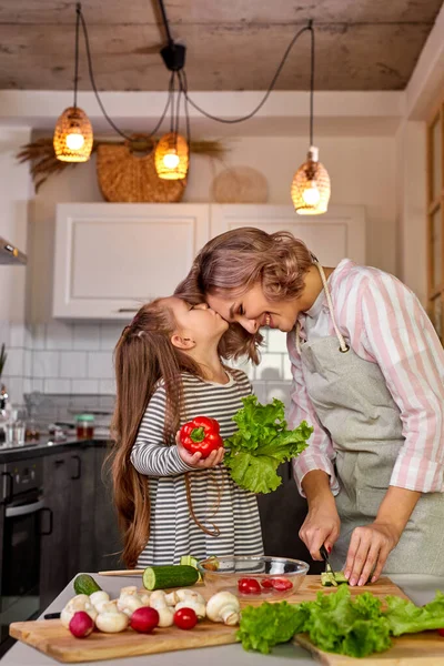 Schöne Mutter und Tochter küssen in der Küche — Stockfoto