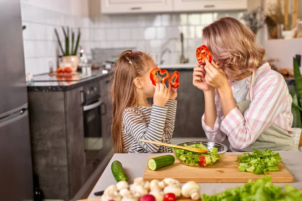 Freudige Mutter und Tochter spielen mit Gemüse in der Küche — Stockfoto