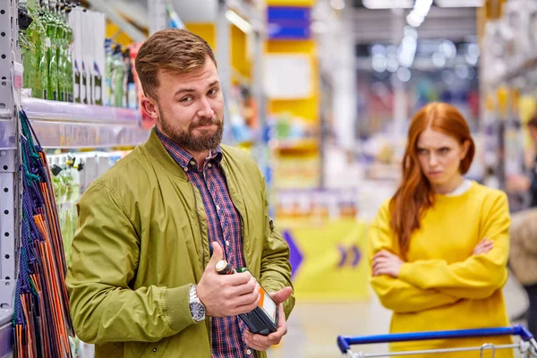 Alkoholmissbrukare man stå med alkohol flaska i händerna medan hennes förolämpade flickvän i bakgrunden — Stockfoto