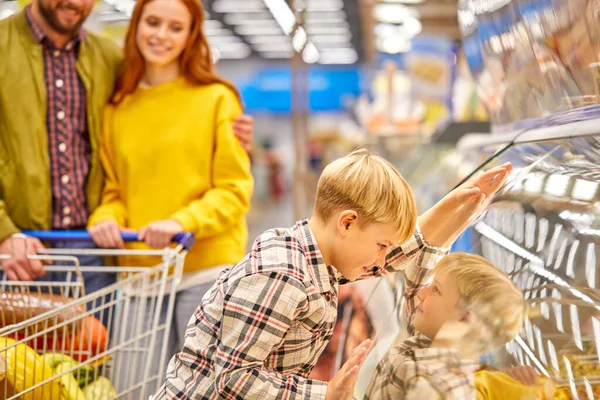 Divertido niño niño se apoyó en escaparate en el supermercado — Foto de Stock