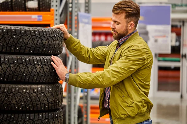 Pohledný chlap vybírá auto pneumatiky v obchodě — Stock fotografie