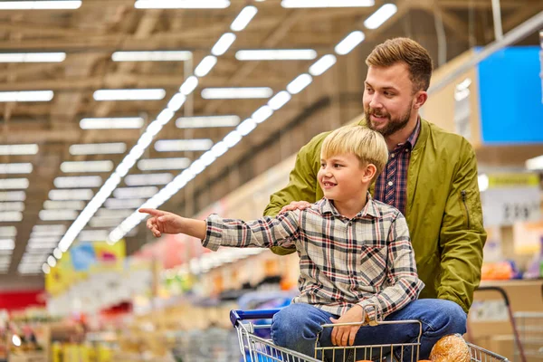 Jongen wijzen vinger naar de zijkant in de winkel tijdens het winkelen met vader — Stockfoto