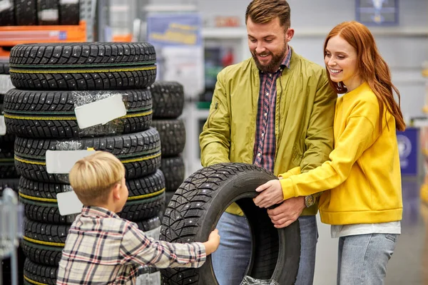 Mladá kavkazská rodina výběr auto pneumatiky v obchodě — Stock fotografie