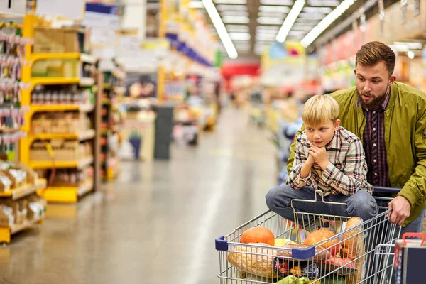 Triest kind jongen zit op kar terwijl zijn vader is winkelen — Stockfoto