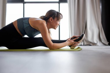 Esnek Asyalı kadın evde paspasın üzerinde geriniyor.