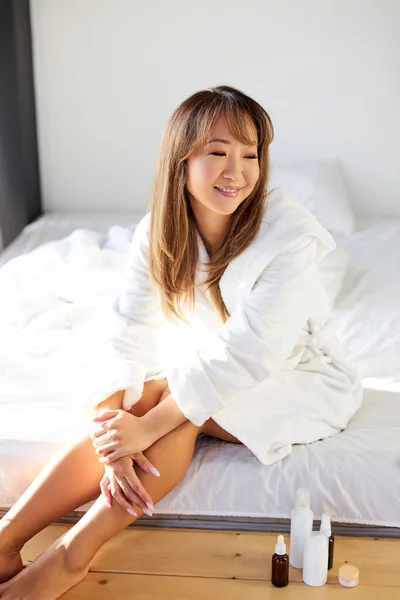 Ung snygg kinesisk kvinna i badrock njuter av släta ben hud — Stockfoto